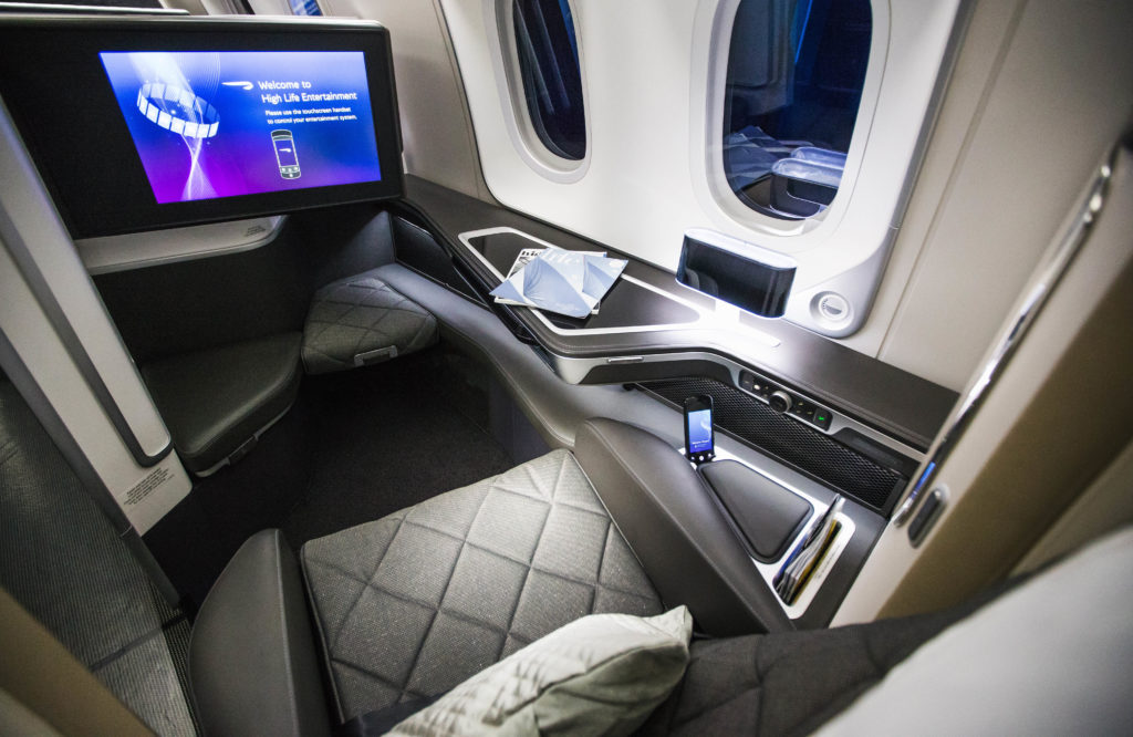 a seat with a screen and a tv on the side of the plane