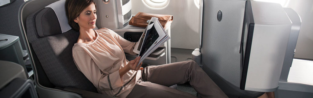 a woman sitting on a plane reading a magazine
