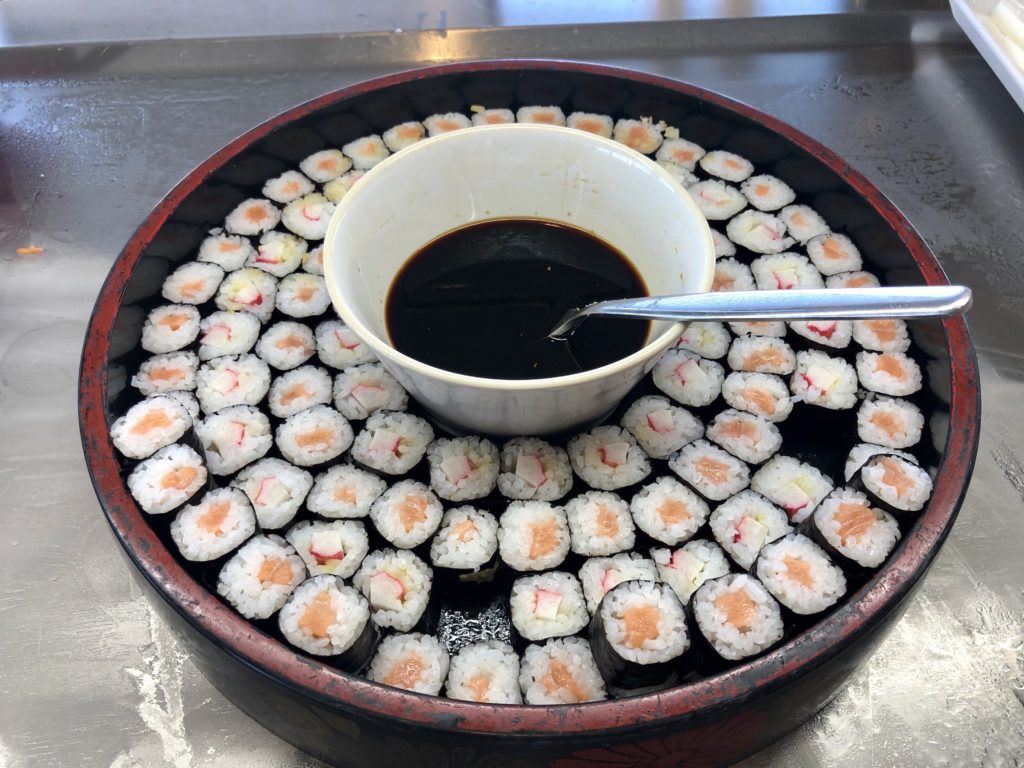 a bowl of sushi with a bowl of soy sauce