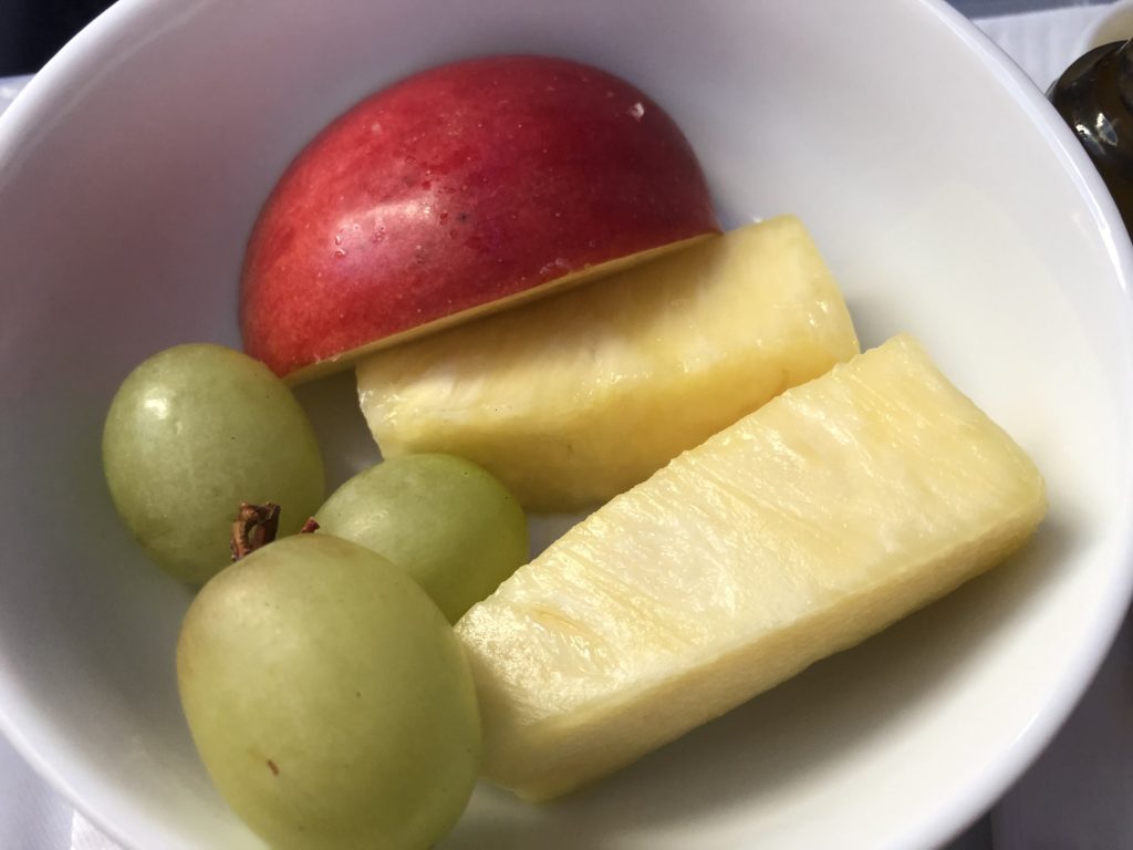 a bowl of fruit with a red apple and grapes