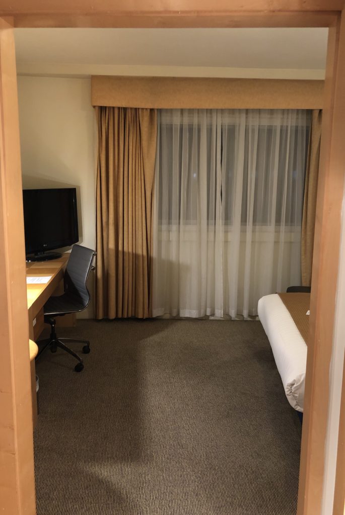 a room with a bed and a desk and curtains