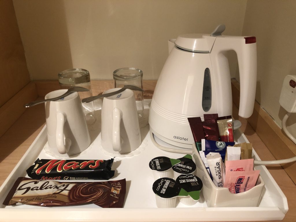 a tray with coffee pot and cups and candy