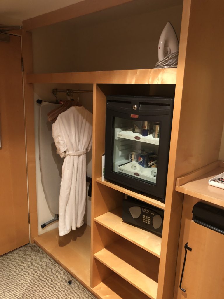 a room with a small refrigerator and a bathrobe