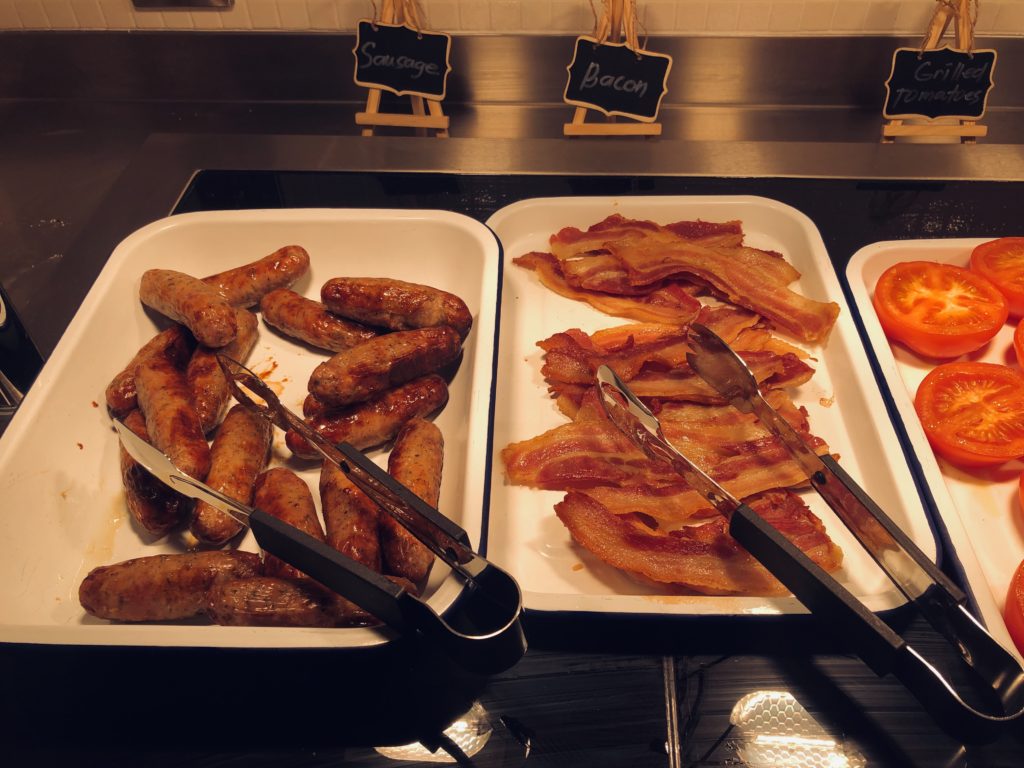 trays of sausages and bacon on a counter