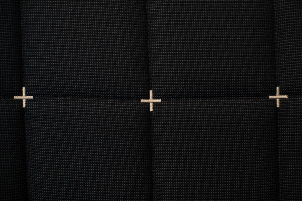 a cross stitch on a black fabric surface