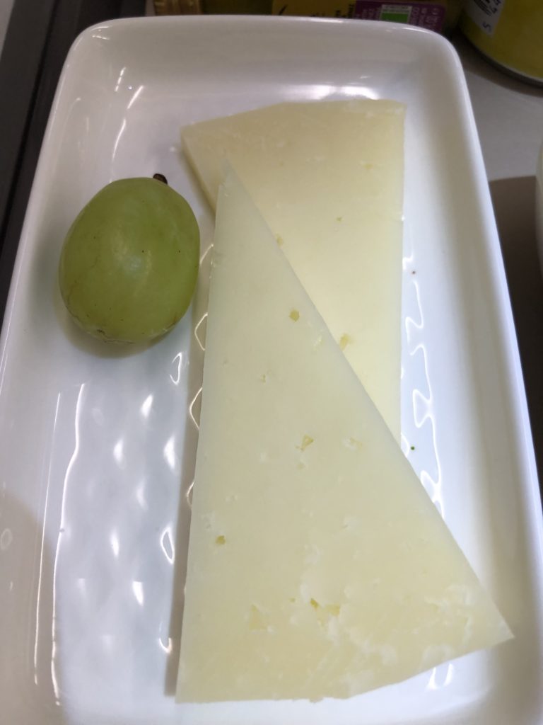 a plate of cheese and a grape