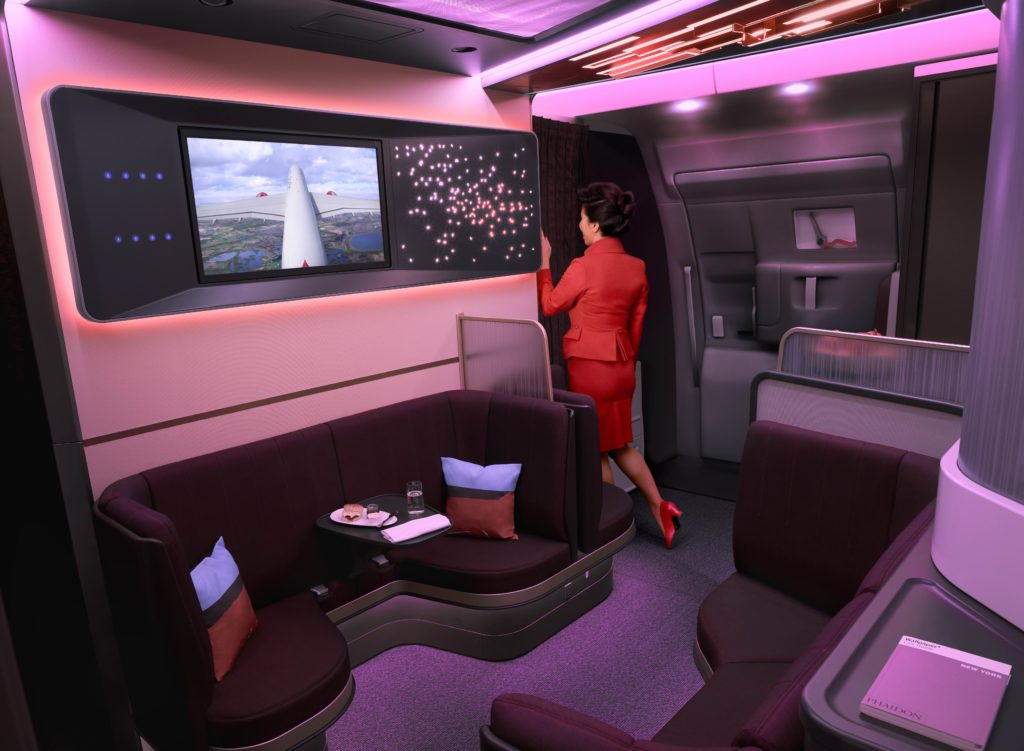 a woman in a red suit standing in a cabin of a plane
